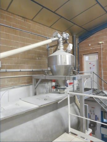 Alimentation d'un mélangeur de premix farine chez Carif alimenté par un vis flexible transitube, via une trémie tampon