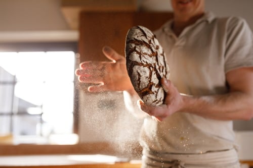 Illustration d'un boulanger tenant un pain de campagne dans les mains avec de la farine