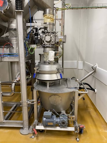 Ligne de transfert de poudre de colostrum chez ECI présentant un tamiseur en sortie de tour de séchage sur un trémie tampon et un transfert par vis vers une ensacheuse