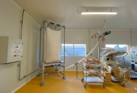 Atelier de préparation de la pâte à pizza chez My Pie avec une station de vidange big bag qui dose automatiquement la farine dans le pétrin