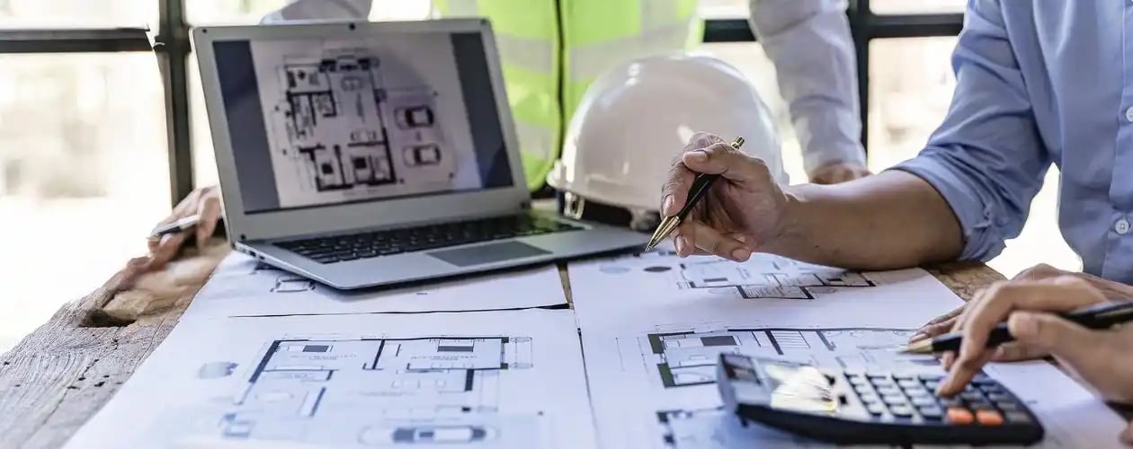 Une réunion de projet autour des plans de l'usine