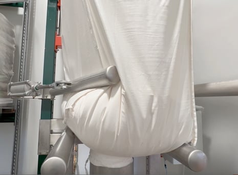 Un big-bags sur une station de vidange assistée par des bras de massage facilitant l'écoulement des poudres