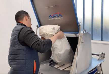 Un opérateur est en train de vider un sacs de poudres alimentaires dans un vide-sacs ergonomique équipé d'un tamisage de sécurité