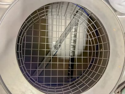 Trémie à fond plat vue de dessus qui montre l'ouverture de gavage de la vis de distribution et la pâle en rotation qui sert de dévouteur pour poudres et ingrédients de mauvais écoulement