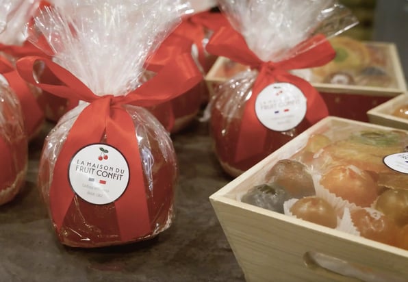 Les fruits confits disponibles dans la boutique Aptunion, un melon, des fruits variés dans une cagette