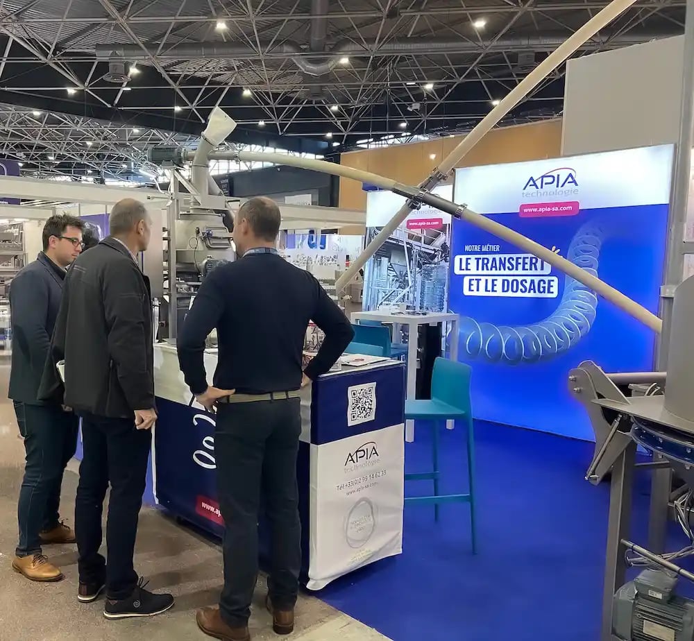 Le stand APIA Technologie au salon du CFIA avec deux vis de transfert en fonctionnement entre une videuse big-bags et une ensacheuse