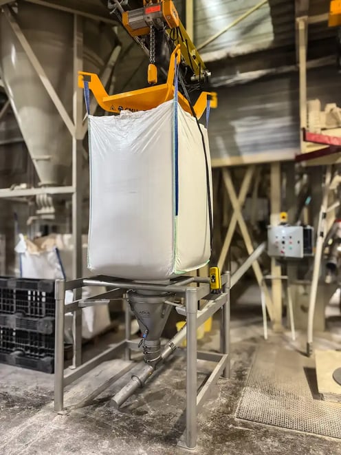 Big bag de céréales vrac positionné par palan au-dessus du poste de vidange sécurisé par APIA Technologie; la vis de transfert relie la trémie conique de réception à l'élévateur à godets