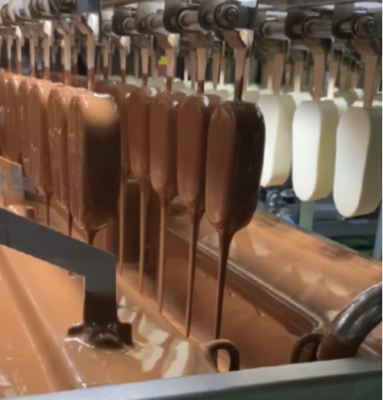 Ligne de fabrication de bâtons glacés au moment de la dépose de l'enrobage chocolat