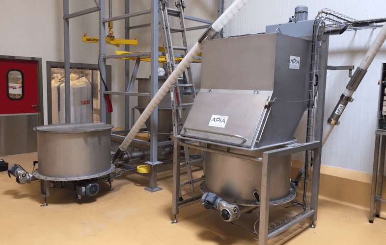 Deux trémies vide-sacs avec fond plat, dont l'une équipé d'une hotte industrielle de dépoussiérage et système de transfert de poudres alimentaires de mauvais écoulement