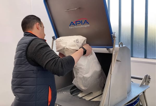 Opérateur en train de vider un sac dans un verse-sacs équipé d'un tamiseur de sécurité