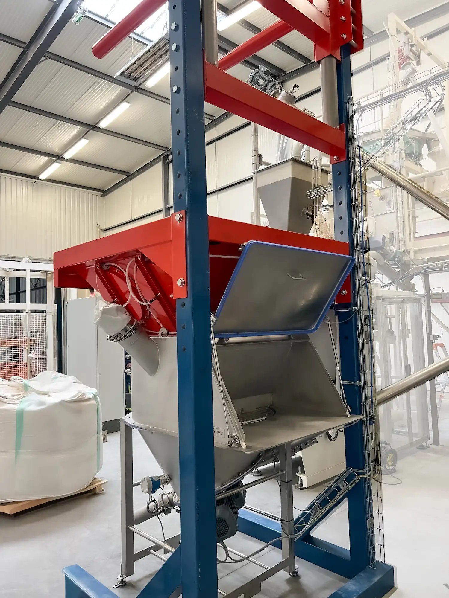 Station de vidange big-bags conçue pour perforer automatiquement les contenants qui se déversent ensuite dans une trémie vide-sacs avec hotte sur mesure