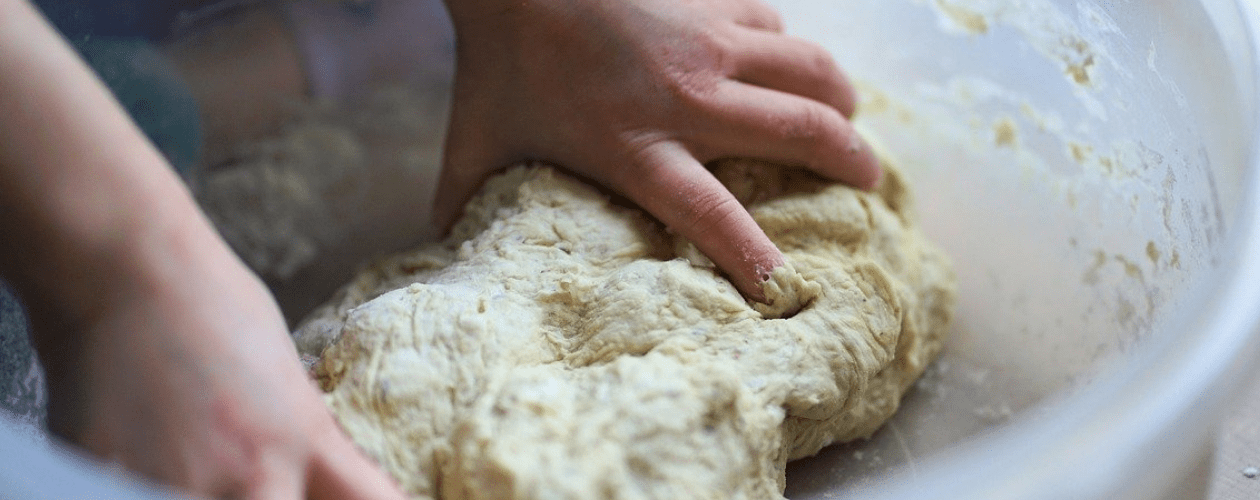 Des mains en train de pétrir une pâte à pain