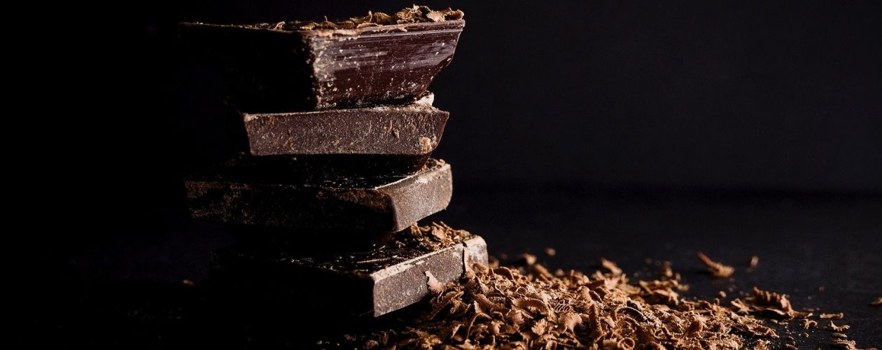 Quelques carrés de chocolat noir empilés et saupoudrés de copeaux