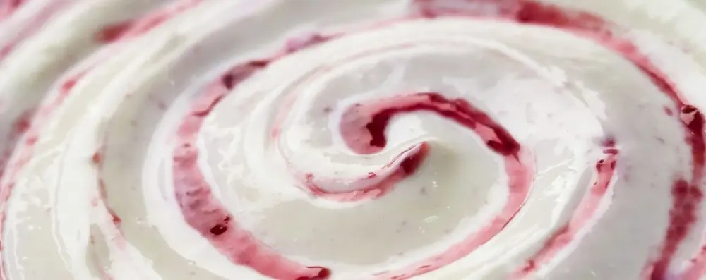 Zoom sur une yaourt mélangé à un coulis de fruits rouges